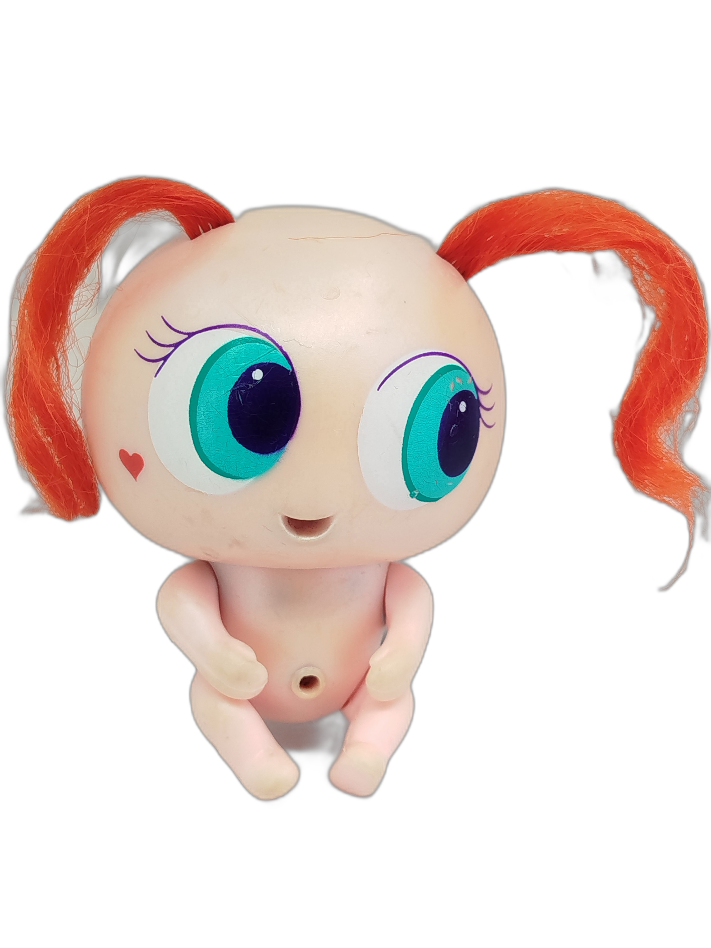 Ksi-Merito Chivatita, la muñeca de color rosa claro, ojos turquesa, un pequeño corazón en la mejilla y dos coletas de pelo color naranja brillante