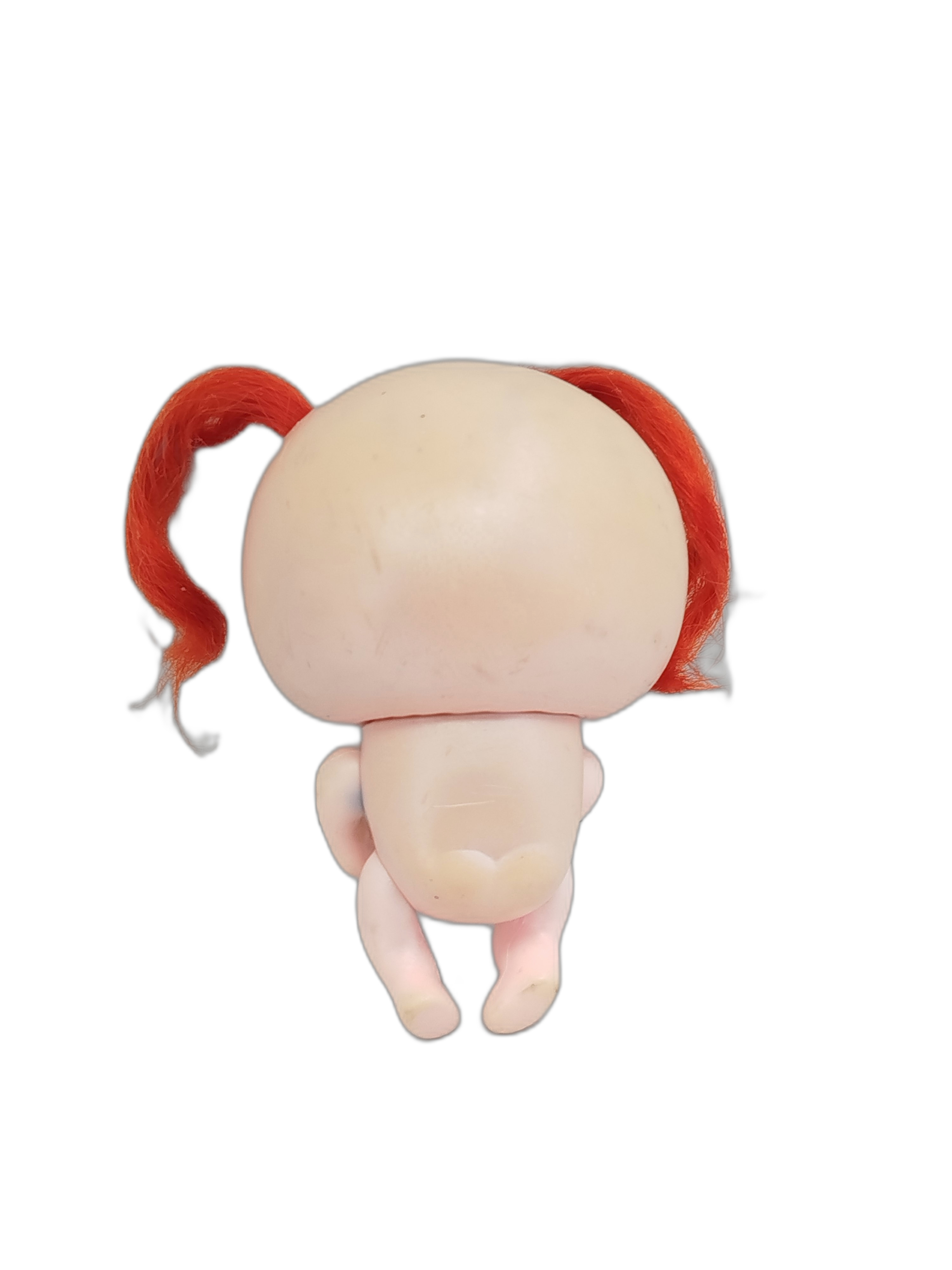 Ksi-Merito Chivatita, la muñeca de color rosa claro, ojos turquesa, un pequeño corazón en la mejilla y dos coletas de pelo color naranja brillante