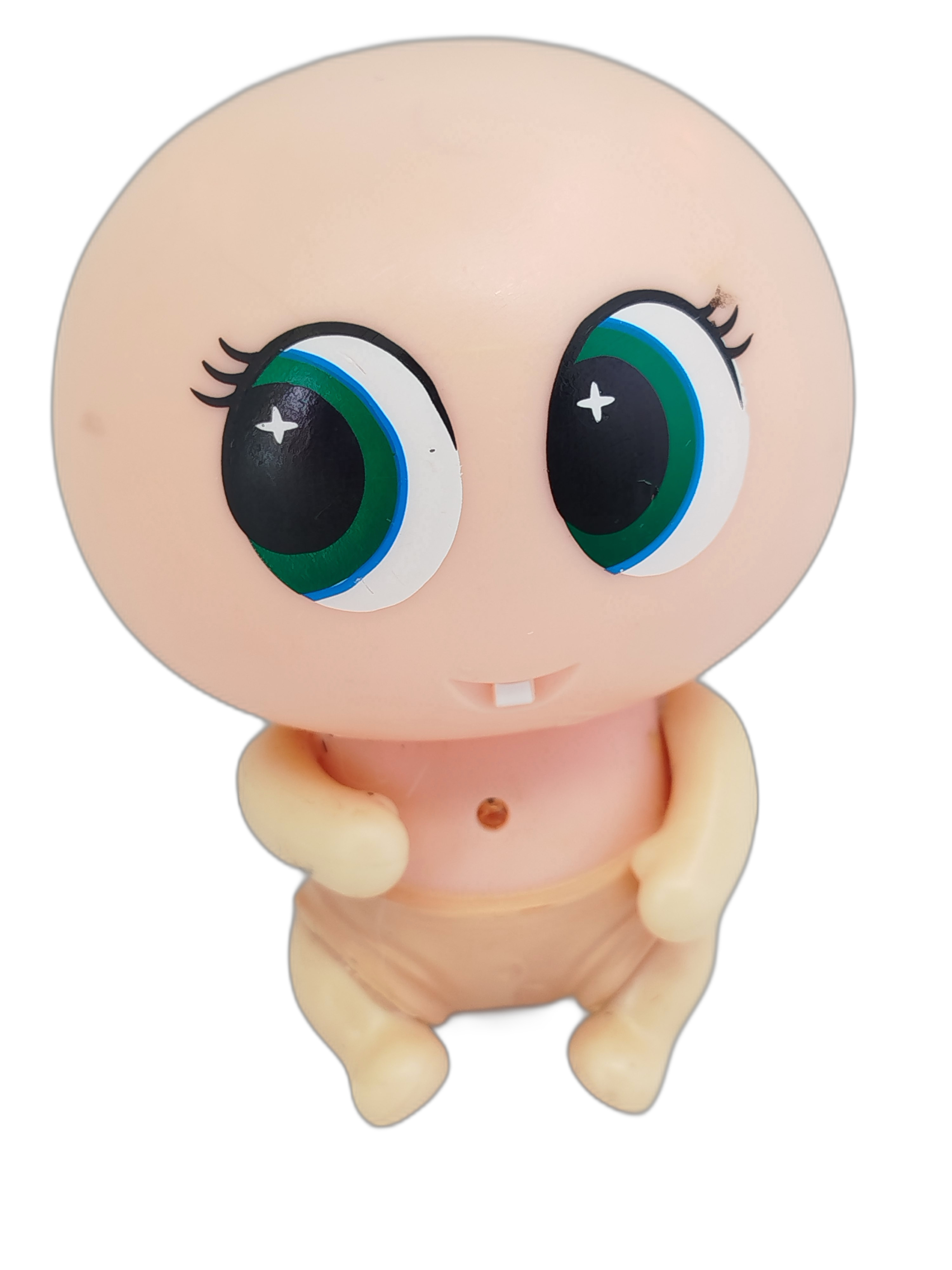 Ksi-Merito  Susikin, la muñeca de piel rosa claro, ojos grandes de color verde y un solo diente visible al centro de la boca