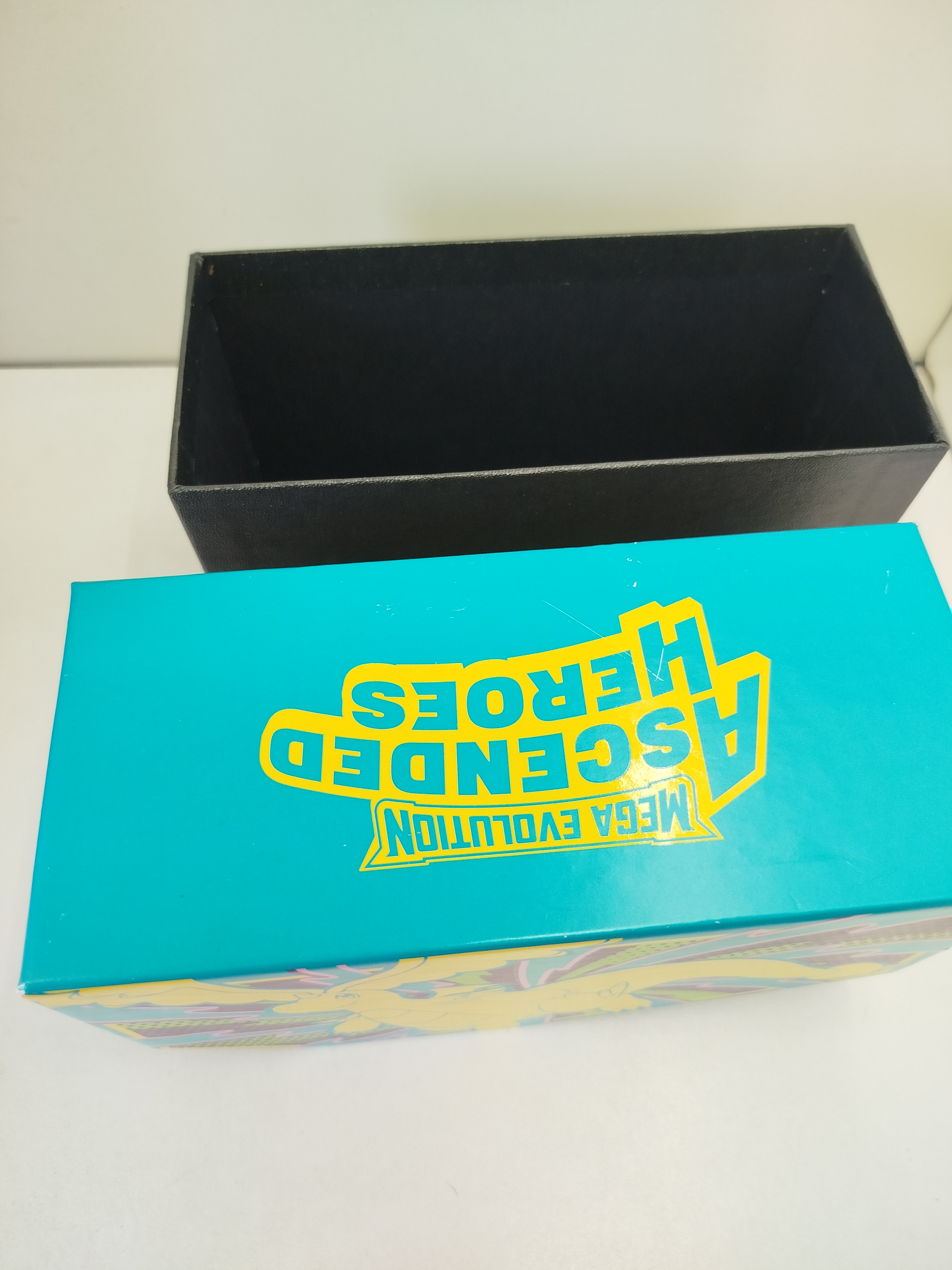 Pokemon - Caja de carton cuenta con un llamativo color azul turquesa y la silueta en tono amarillo de Mega-Dragonite