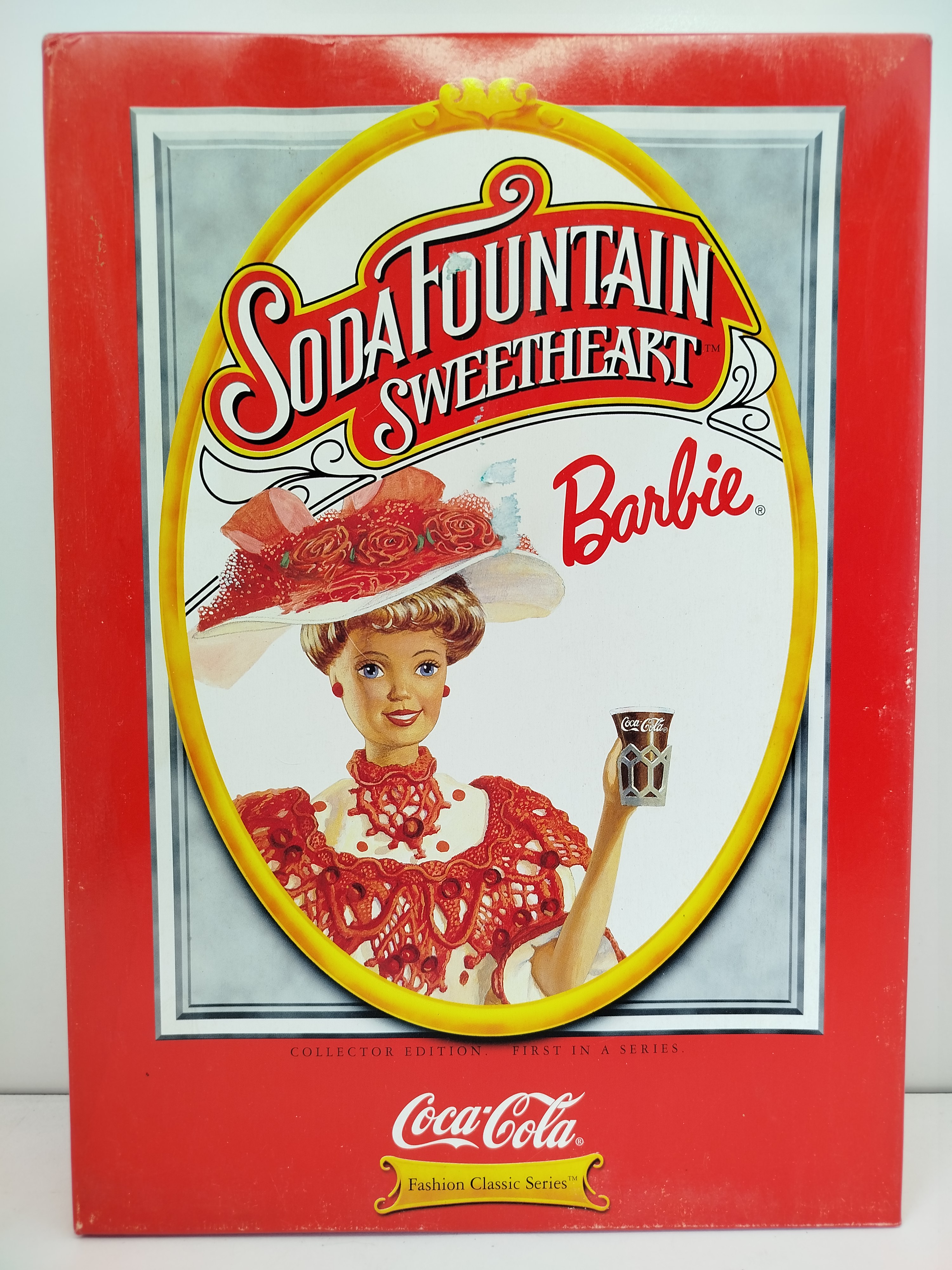 Soda Fountain Sweetheart Barbie, lanzada por Mattel en 1996 como la primera pieza de la serie Coca-Cola Fashion Classic Series - (CAJA CON DESGASTE)