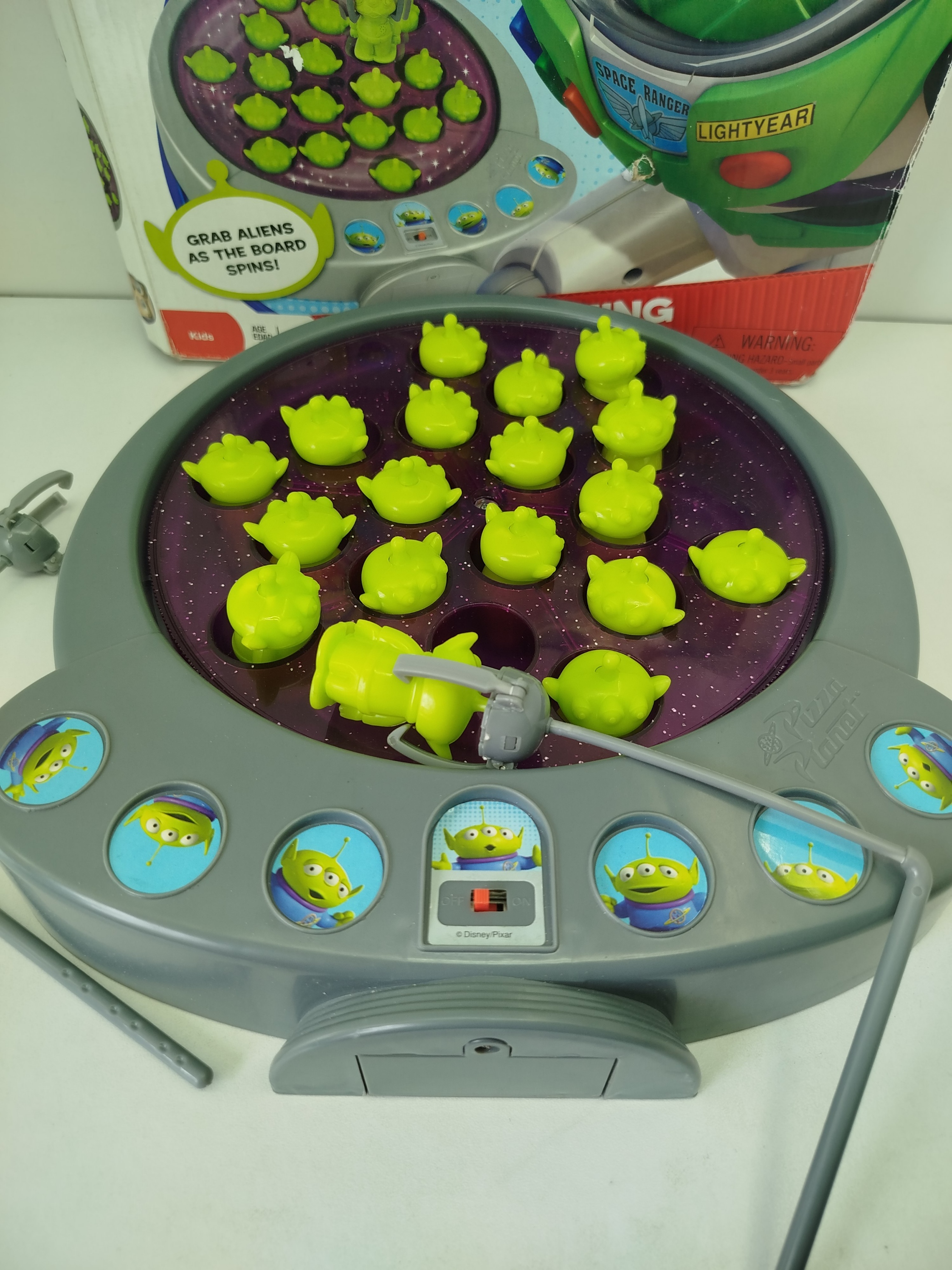  Toy Story 3 Alien Fishing Game-  juego de pesca motorizado, se utiliza cañas con "garras" para atrapar a  marcianitos verdes de Pizza Planet mientras el tablero gira.