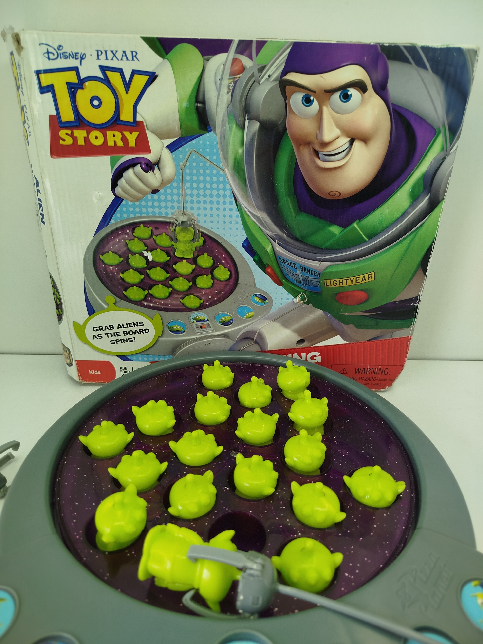  Toy Story 3 Alien Fishing Game-  juego de pesca motorizado, se utiliza cañas con "garras" para atrapar a  marcianitos verdes de Pizza Planet mientras el tablero gira.